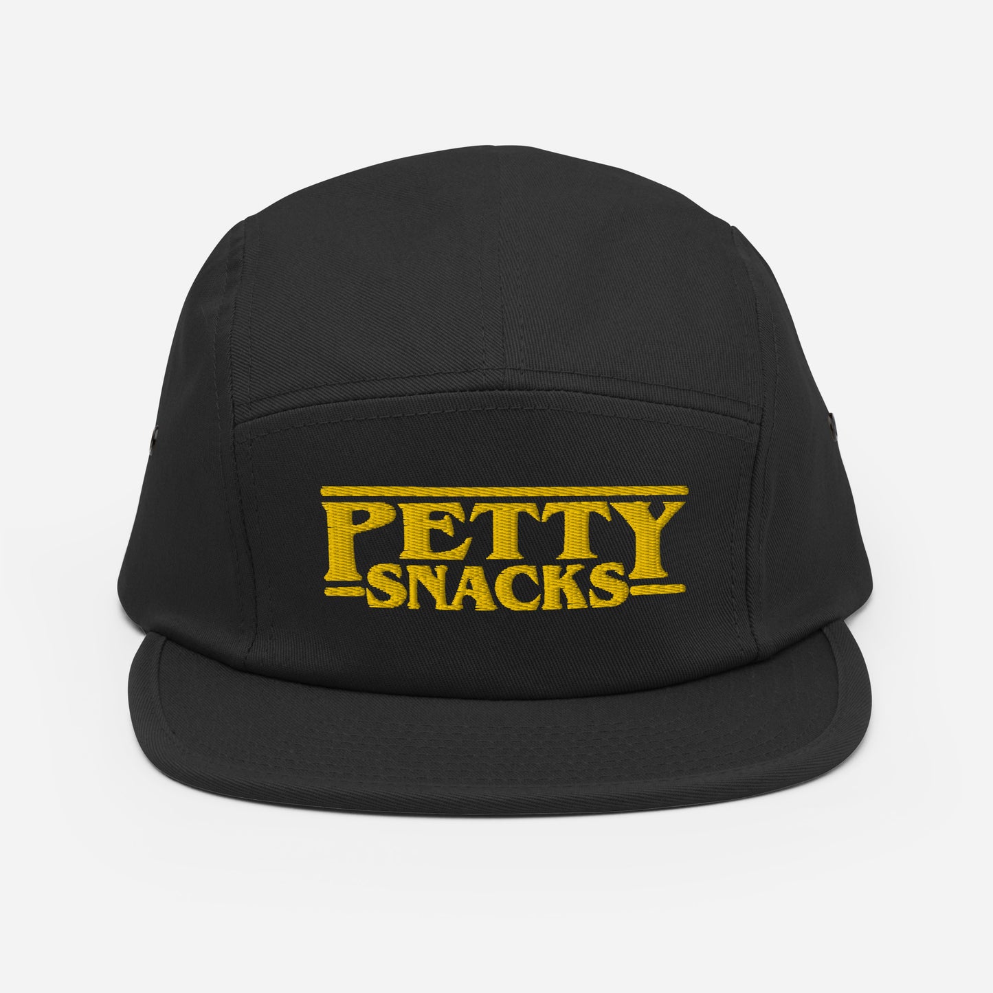 A black five-panel hat with embroidered lettering in front center. Letterings says "Petty Snacks" in yellow with a line on top and bottom of the words. In the style of film credits made famous by Tarantino.