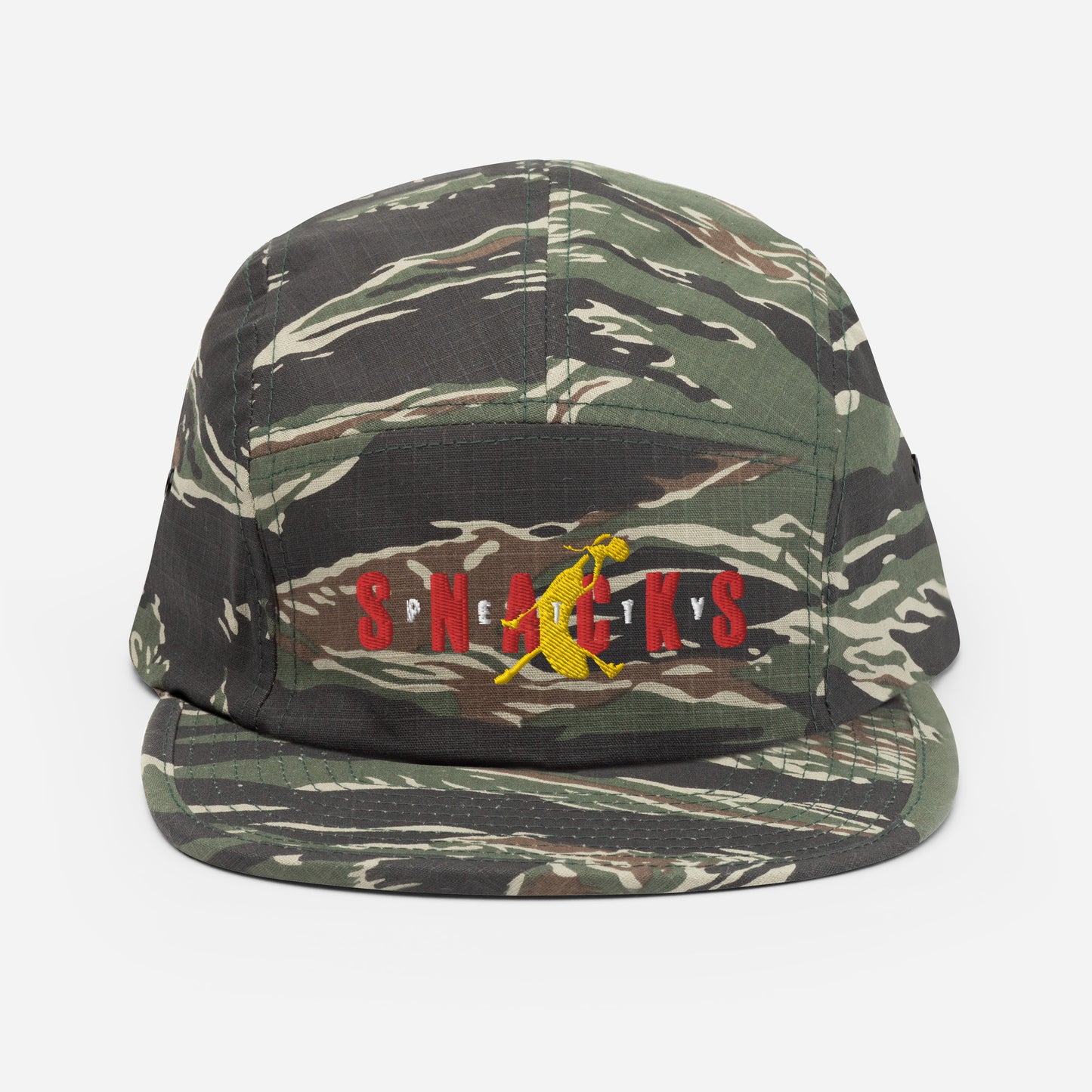 Green tiger camo five panel hat, front panel has embroidered graphic. "Petty Snacks" with a jumpan inspired logo that is a yellow banana duking a bong. The word "Snacks" is big and spread across front in red. The word "PETTY" is small lettering, with each letter in between the letter of "Snacks" and over the banana. Logo is inspired by jumpman graphic