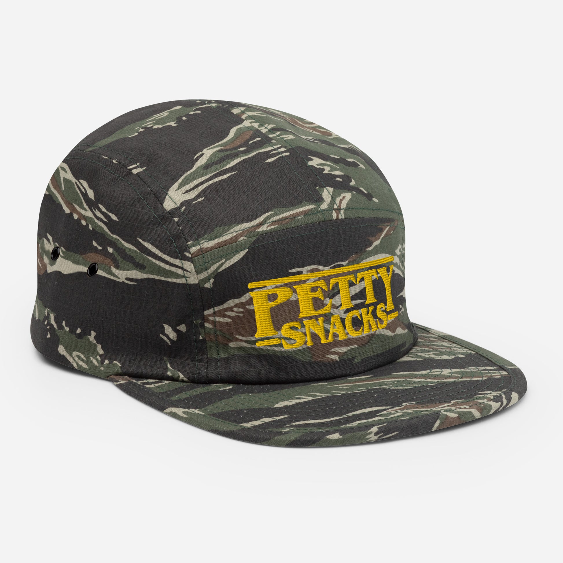 A side view of a green tiger-camo five-panel hat with embroidered lettering in front center. Letterings says "Petty Snacks" in yellow with a line on top and bottom of the words. In the style of film credits made famous by Tarantino.