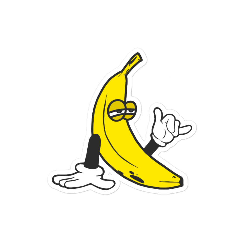 Sticker of a yellow banana with stoney eyes, black arms and white cartoon gloves. One hand resting on ground, back hand holding up a shaka hand gesture